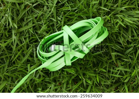 Charger wire green color put on grass background represent the mobile phone device equipment material related.