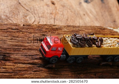 Coffee beans on old hard wood with toy truck model represent coffee business concept related idea . Super macro shot and intention focus at the truck.