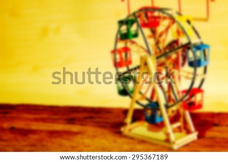 The blurry photo of ferris wheel toy model with multicolor light at the back on lomography style represent the toy and amusement background concept related idea.