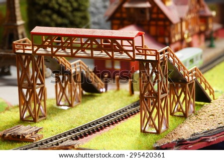 Old and dirty plastic model of pedestrian bridge across model railway track represent the model train toy equipment concept related idea.