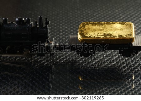 Gold bar put on the on the model railroad flatcar represent the business concept related idea.