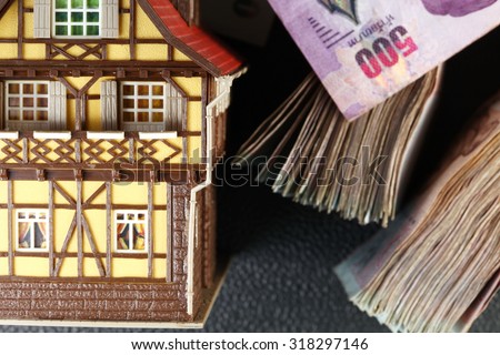 Old and dirty plastic house model put beside blurry focus of banknote represent the home loan and mortgage concept related idea.