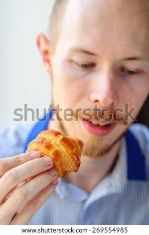 Man eats croissant for breakfast