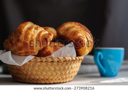 Breakfast with fresh baked croissants, butter and coffee on white wooden background