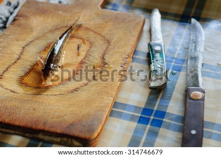 Cleaning and gutting little river fish in country kitchen
