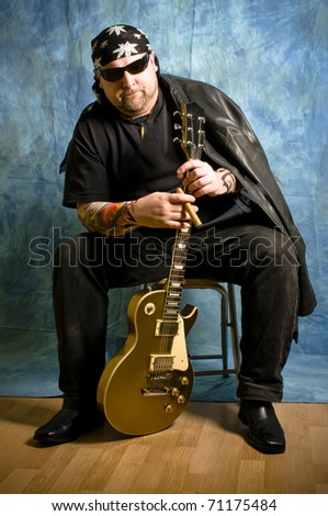 Rock musician pose with a guitar and holds cigar