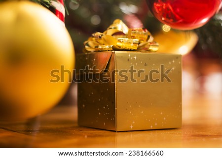 Golden gift box  with golden bow placed on the floor under the Christmas tree