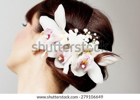 Bride is posing her hair style with orchids for her wedding day. Bride has bangs.