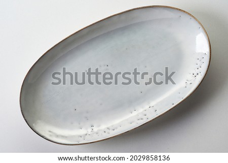 An oval-shaped white ceramic plate with a golden rim on white background ストックフォト © 