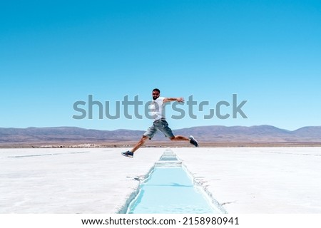 A closeup of a man jumping over a water in Salinas Grandes, Argentina Foto stock © 