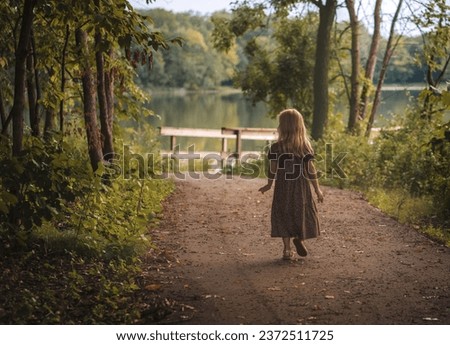 Similar – Image, Stock Photo Little girl walks by the hand of her mother and looks back smiling with a swing in her hair.