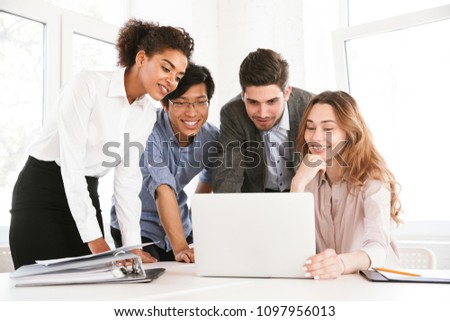 Group of smart young multiethnic businesspeople discussing ideas while looking at laptop computer