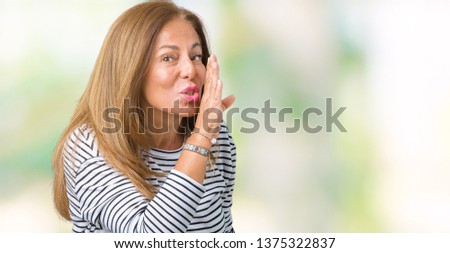 Beautiful middle age woman wearing stripes sweater over isolated background hand on mouth telling secret rumor, whispering malicious talk conversation