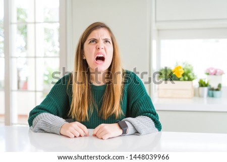 Young beautiful plus size woman wearing casual striped sweater angry and mad screaming frustrated and furious, shouting with anger. Rage and aggressive concept.