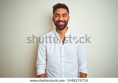 Young indian man wearing elegant shirt standing over isolated white background with a happy and cool smile on face. Lucky person.