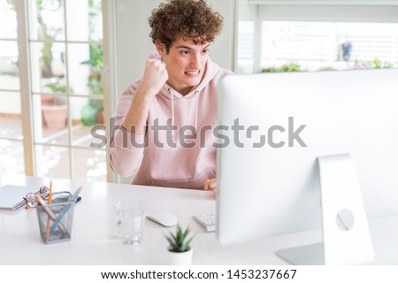 Young student man using computer annoyed and frustrated shouting with anger, crazy and yelling with raised hand, anger concept