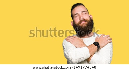 Young hipster man wearing winter sweater Hugging oneself happy and positive, smiling confident. Self love and self care