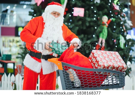 Santa Claus with gifts in a shopping cart in the mall.