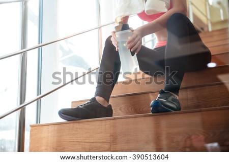 Closeup of attractive sportswoman sitting and drinking water