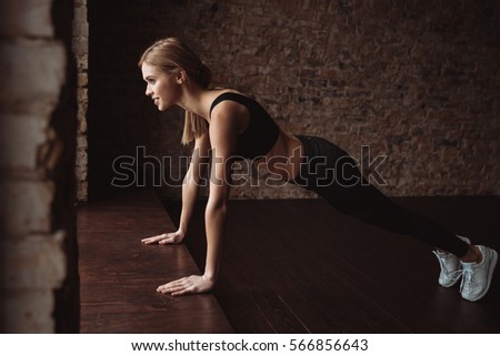 Happy young sportswoman doing pushups on the floor