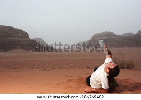 Desperate man in the desert drinking last drops of water from an empty bottle