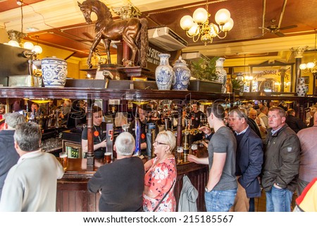 Glasgow, Scotland, UK - 23 August 2014: People drinking and watching football in The Horseshue Bar in Glasgow on the longest bar in Europe (104 feet and 3 inches).