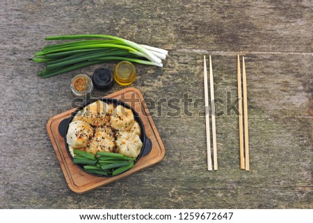 Chinese dumplings with soy sauce, green onions and sesame in a cast iron skillet. Dumplings in the Chinese style in a griddle.