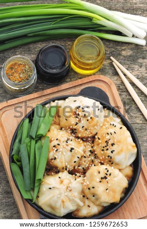 Chinese dumplings with soy sauce, green onions and sesame in a cast iron skillet. Dumplings in the Chinese style in a griddle.