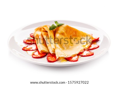 Tasty crepes with strawberries on white background