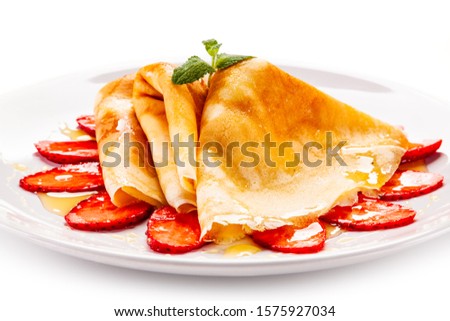 Tasty crepes with strawberries on white background