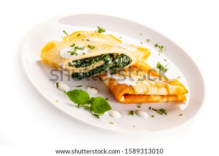Crepes with spinach and feta cheese on white background
