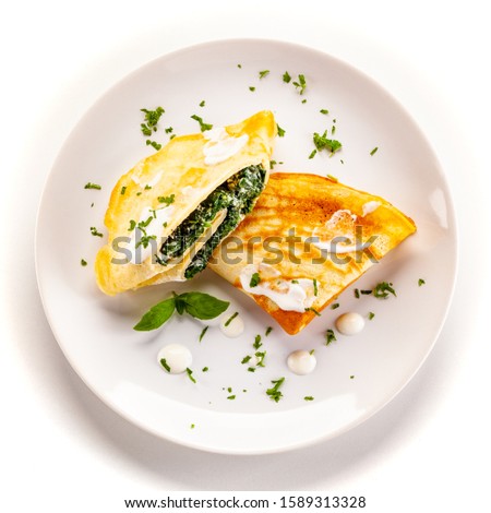 Crepes with spinach and feta cheese on white background