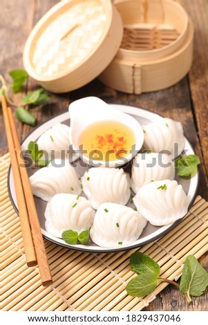 traditional chinese steamed dumplings dim sums in bamboo steamer and chopsticks