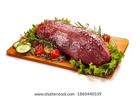 Fresh raw beef on cutting board with fresh vegetables on white background 