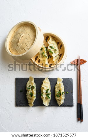 steamed dumpling in traditional wooden steamer and black stone slate on white texture stone background top view