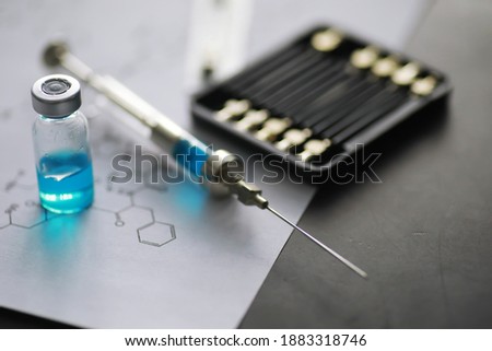 small jars with injection and syringe for injection on blue background near the chemical formula
