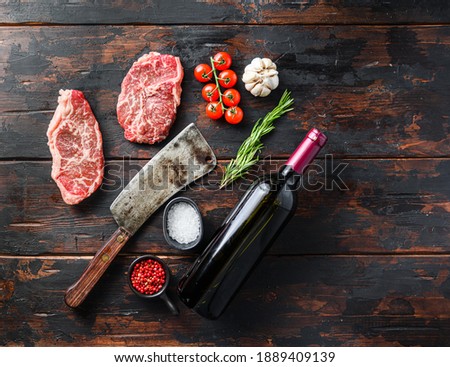 steak à la lame organique, viande de boeuf cru aux assaisonnements, rôtisseur de romarin et de boucher et bouteille de vin rouge. Arrière-plan texture bois. Espace panoramique pour le texte