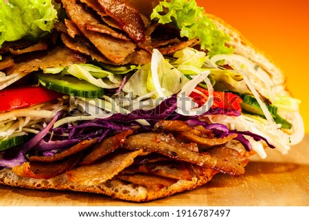 Kebab - grilled meat, bread and vegetables against orange gradient background