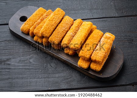 Frozen fish Sticks set, on wooden cutting board, on black wooden table background