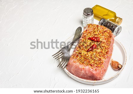 Raw organic meat. Pork fillet for grilling, baking, or frying. Flakes spices, cutlery, oil on a white putty background, copy space