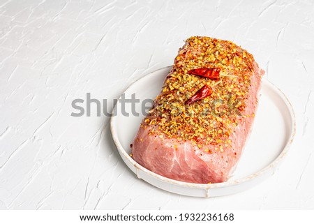 Raw organic meat. Pork fillet for grilling, baking or frying. Flakes spices, ceramic plate on white putty background, copy space