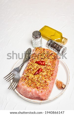 Raw organic meat. Pork fillet for grilling, baking, or frying. Flakes spices, cutlery, oil on a white putty background, copy space