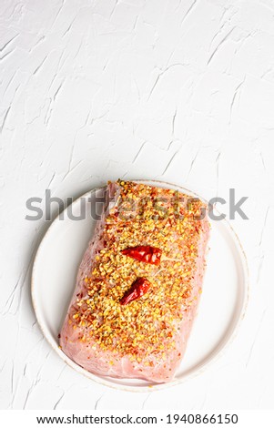 Raw organic meat. Pork fillet for grilling, baking or frying. Flakes spices, ceramic plate on white putty background, top view