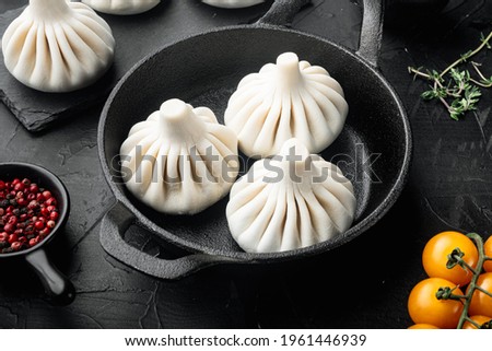 Homemade, traditional chinese pan fried dumplings set, in frying cast iron pan, on black stone background