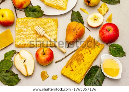 Rosh Hashanah celebration concept with traditional symbols. Jewish New Year holiday with fresh apples and pears, liquid honey and honeycombs. Light stone concrete background, top view