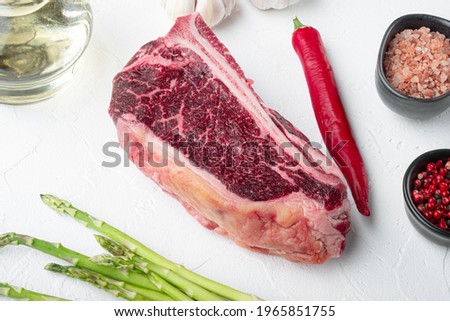Fresh raw club steak with the salt, garlic and herbs set, on white stone background