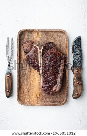T-bone grilled beef steak with spices and herbs set, on wooden tray, top view flat lay