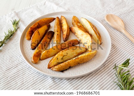 Homemade Rosemary Potato Wedges on a plate, side view. 