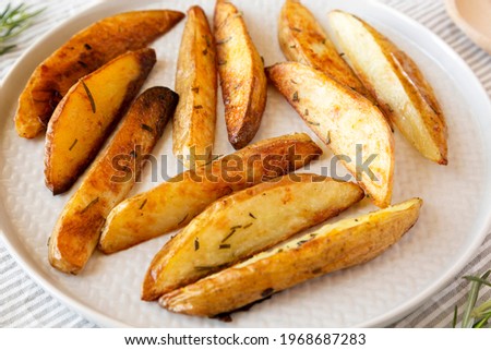Homemade Rosemary Potato Wedges on a plate, side view. Close-up.