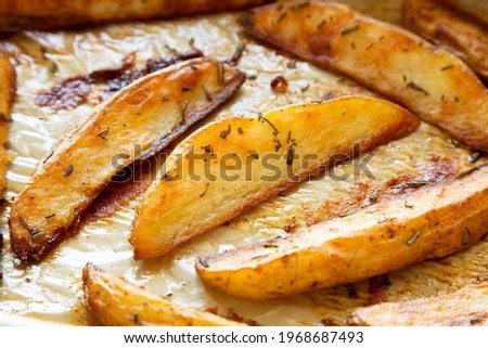 Homemade Rosemary Potato Wedges on a baking tray, side view. Close-up.
